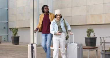 Farklı çiftler plazadan çıkıyorlar. Bagajlarını taşıyorlar. Kadın akıllı telefon kaydırıyor. Gezginler, şehir, yaşam tarzı, modern mimari, hareketlilik, gelişigüzel, macera