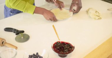 Çeşitli çiftler mutfakta hamuru turta tabağına sıkıştırıyor hamuru pürüzsüz hale getiriyorlar yemek pişirmek için kırıntıları yoğuruyorlar. Yemek pişirme, takım çalışması, aşçılık, modern, canlı, taze, hazırlık