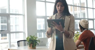 Ofisteki çeşitli iş arkadaşları, iş arkadaşları dizüstü bilgisayarda yazarken tableti alarma geçiriyorlar. İşbirliği, teknoloji, girişim, üretkenlik, modern, profesyonel, işyeri