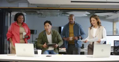 Çeşitli iş arkadaşları toplanmak için masanın etrafında toplanıyor, tablet aşırıyor ve dizüstü bilgisayarın ekranını renklendiriyor. İşbirliği, takım çalışması, yenilik, ofis, teknoloji, beyin fırtınası, profesyonel