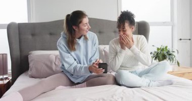 Yatakta akıllı telefon gösteren, komik içeriği paylaşan, gülen ve kaydıran çeşitli bayan arkadaşlar. Gündelik, dostluk, rahatlama, yaşam tarzı, ev, samimiyet.