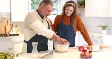 Ekmek pişirmek ve mutfak adasında hamur yoğurmak için tezgahın üzerine temiz karıştırma kabı koyan bir çift. Çift, pişirme, aşçılık, ev yemeği, yaşam tarzı, rahat, neşeli