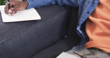 Afro-Amerikalı bir adam dizüstü bilgisayarda yazı yazıyor, sonra da akıllı telefonu arıyor. Üretkenlik, modern, gündelik, ev, teknoloji, iletişim, konsantrasyon