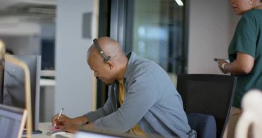 Afrika kökenli Amerikalı erkek yazı masasında elinde akıllı telefon tutan iş arkadaşı başparmak işareti yapıyor. İşbirliği, iletişim, üretkenlik, takım çalışması, modern, profesyonel, enerjik