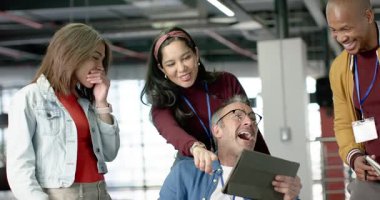 Tabletin etrafında toplanan çeşitli iş arkadaşları Hintli kadının işaret ettiği adam kahkahalar atıyor. İşbirliği, takım çalışması, yenilik, modern, profesyonel, dijital, beyin fırtınası