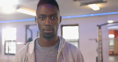 Afro-Amerikan bir adam ayakta duruyor ve ciddi olmaktan çıkıp spor salonunda gülüyor. Güven, sağlık, fitness, ifade, modern, pozitif, sağlık