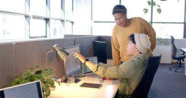 Çalışma masasında çeşitli iş arkadaşları var. Biri çift ekrana bakıyor ve görüşlerini paylaşıyor. İşbirliği, üretkenlik, modern, profesyonel, iletişim, takım çalışması, dijital