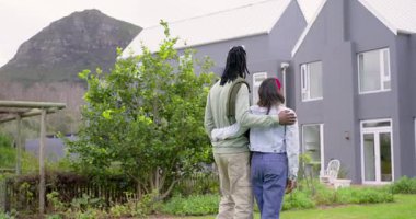 Bahçedeki gri iki katlı eve yaklaşan çeşitli çiftler ev özelliklerini değerlendirirken işaret ediyorlar. Romantik, mimari, manzara, tefekkür, samimiyet, açık hava, modern