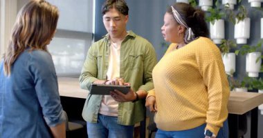 Meslektaşları tezgahta içeriği görmek için başını sallarken Asyalı bir adam tableti tıkırdatıyor. İşbirliği, takım çalışması, yenilik, modern, teknoloji, tartışma, çalışma alanı