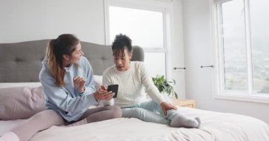 Çeşitli bayan arkadaşlar, komik online videolar paylaşmak için yatağa akıllı telefonları kaydırırken öne eğiliyor. Arkadaşlık, bağlantı, rahat, rahat, sohbet, teknoloji, yaşam tarzı