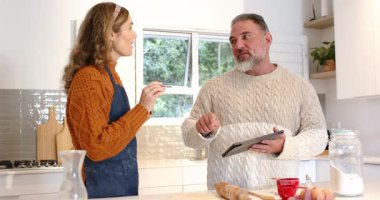 Detayları ölçmek ve tablet tarifini kaydırmak için gelen çift, sonra da tezgahta hamur hazırlıyor. Aile içi, aşçılık, yaşam tarzı, modern, parlak, işbirlikçi, erdemli.