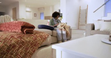 Bir kadın aşağıya bakıyor, oturma odasında kanepenin üzerinde altın köpeği kucağına çekiyor, karnını okşuyor. Modern, samimi, sevecen, evcil hayvan, rahatlama, ev, yaşam tarzı