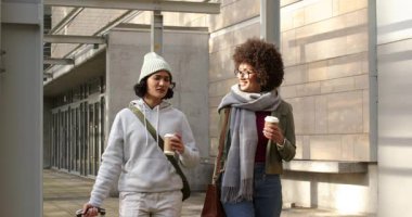 Kahve fincanlarını aldıktan sonra muhabbet ederken çantalarını çeken iki kadın. Kentsel, gündelik, arkadaşlık, yaşam tarzı, modern, canlı, yürüyüş