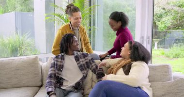 Çeşitli arkadaşlar sohbet eder, alkışlar, kameraya döner, kanepede gülerek kapıyı sürgüler. Sosyalleşme, bağlantı, rahat, rahat, modern, mutluluk, açık hava