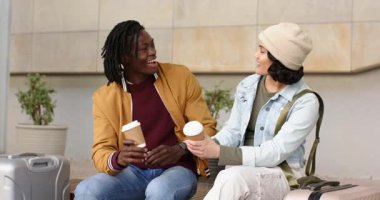 Kadeh kaldırmak için kahve fincanlarına dokunan, sohbet eden ve banktaki bavulların arasında kucaklaşan bir çift. Romantizm, arkadaşlık, şehir, yaşam tarzı, samimiyet, bağlantı, eğlence