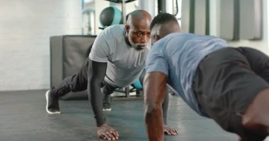 Afro-Amerikan antrenör ve müşteri şınav çekerek ilaç toplarını destekliyor. Fitness, takım çalışması, motivasyon, güç, işbirliği, spor giyimi, eğitim