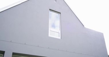 Kamera gable çatıdan aşağı eğilmiş, sürgülü kapıları ortaya çıkarmış, yaşam alanını ve bahçe yolunu göstermiş. Mimari, konut, minimalist, çağdaş, açık hava, peyzaj, iç mekan