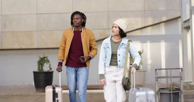 Binanın yanında yürüyen, bavullarını çeken akıllı telefon ekranlarını kontrol eden çeşitli çiftler var. Seyahat, macera, şehir, yaşam tarzı, navigasyon, modern, keşif