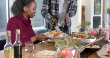 Afro-Amerikalı çift bıçaklarını kapıp kapısının yanındaki tabağa tavuk koyuyorlar. Romantik, keyifli, hoşgörülü, aşçı, evcil, sıcak, uyumlu.