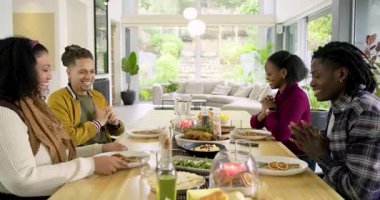 Çeşitli arkadaşlar yemek masasının etrafına mısır atmadan önce el sıkışıyorlar. Topluluk, bağlantı, sıcaklık, neşe, masa, kutlama, birliktelik.