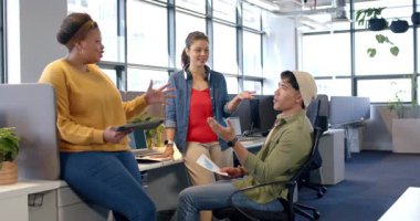 Basılı çizelgeyi gözden geçiriyorlar, çeşitli iş arkadaşları ofis masasındaki tabletteki verileri tartışıyorlar. İşbirliği, takım çalışması, yenilik, modern, profesyonel, kentsel, dinamik