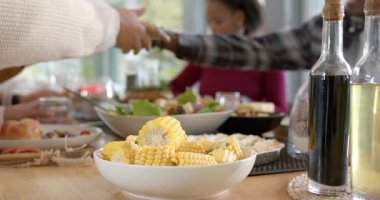 Afro-Amerikalı kadın evde salata ve mısır servisi yaparken gülümseyerek su alan elleri izliyor. Aile toplantısı, toplu yemek, sosyal bağlantı, sağlıklı, yaşam tarzı, kırsal, modern