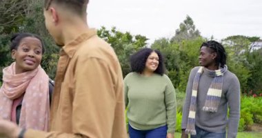 Gri süveter giyen, arkadaşlarının sırtına binmek için koşan farklı arkadaşlar. Doğa, arkadaşlık, açık hava, eğlence, neşe, yaşam tarzı, gelişigüzel