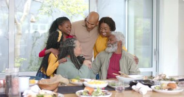 Geniş aile, dedelerle evde sohbet ederken ve su sürahisinin üzerine eğilip gülümserken. Aile, çok nesilli, birliktelik, aile içi, samimi, rahat, sıcak