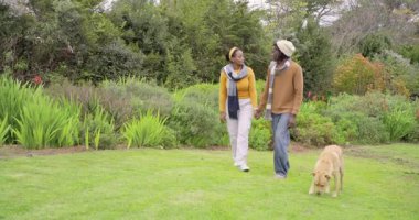 Afroamerikan çift bahçeye giriyor, el ele tutuşuyorlar, esmer köpek otları kokluyor, neşeyi paylaşıyor. Romantik, arkadaşlık, doğa, rahatlık, dinginlik, yeşillik, bağlantı