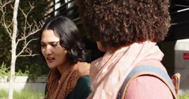 Dışarıdaki bankta sırt çantaları takan çeşitli bayan arkadaşlar, hoparlör her bakışta endişeyi açıklıyor. Açık hava, arkadaşlık, iletişim, kentsel, boş zaman, samimi, çağdaş