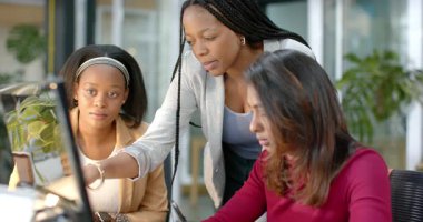 Masaya yaslanmış çeşitli kadın iş arkadaşları ekranı işaret ederek detayları karşılaştırıyor. İşbirliği, takım çalışması, iletişim, modern, profesyonel, beyin fırtınası, jest