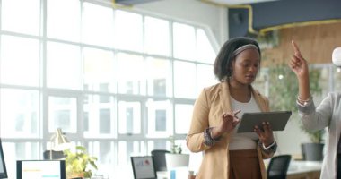 Afro-Amerikalı kadınlar, VR kulaklık kullanıcısının parmak kaldırması ve ofiste test etmesi üzerine tableti inceliyorlar. Teknoloji, işbirliği, yenilik, profesyonel, modern, dijital, çalışma alanı