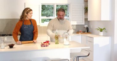 Birkaç rulo hamuru mutfak adasında iğne kullanarak yuvarlıyor sonra da pişirmeyi kutlamak için şarap ve tost dolduruyorlar. Romantik, kutlama, samimiyet, yaşam tarzı, çağdaş, samimi, birliktelik