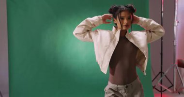 Stüdyoda yeşil arka planda poz veren şık ceketli kendine güvenen bir kadın. Moda, güven, portre, tarz, zarafet