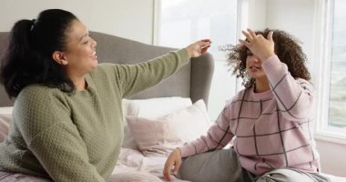 Anne ve kızı yatakta buklelerle alay ediyor. Sonra da kız, anne dinleyerek boyun ağrısını açıklıyor. Sevgi, bağlantı, sıcaklık, rahatlık, bakım, aile, ev