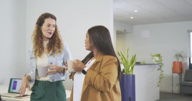 Kahve fincanlarıyla ofise giriyorlar, çeşitli kadın iş arkadaşları molada laptopun başına yürüyüp sohbet ediyorlar. İşbirlikçi, profesyonel, gündelik, modern, dostane, iletişim, çalışma alanı