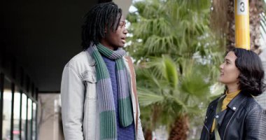 Afro-Amerikalı bir adam kaldırımda bir kadına doğru dönüyor, 3. direğin orada otobüs durağı hakkında sohbet ediyor. Kentsel, bağlantı, iletişim, arkadaşlık, gündelik, samimi, anlamlı