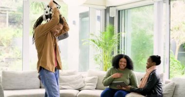 Çeşitli arkadaşlar VR kulaklıklarını ayarlıyor ve kadınların oturma odasında kulaklık takmalarına yardım ediyorlar. İşbirliği, teknoloji, çağdaş, eğlence, eğlence, yaşam tarzı, etkileşim