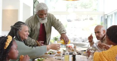 Çeşitli aile ahşap masanın etrafında toplanıyor ve yaşlılar kadehlere portakal suyu döküyor. Aile, yemek, yemek, birliktelik, iç mekan, kutlama, topluluk
