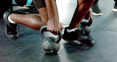 Afrika kökenli Amerikalı bir adam beden eğitimi dersinde kettlebell ile ters hamleler yapıyor. Güç, fitness, egzersiz, eğitim, dayanıklılık, atletizm, sağlık