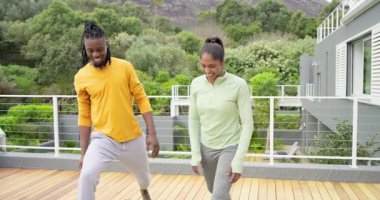 Çeşitli çiftler kollarını kaldırıp savaşçı 2 'ye balkon minderlerinde yoga yaparken beşlik çakıyorlar. Spor, sağlık, farkındalık, denge, açık hava, uyum, eğitim