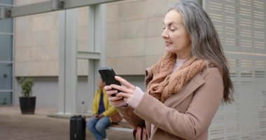 Değişik kadınlar ulaşım platformuna geliyor, tren tarifesi için akıllı telefonları dinliyorlar, kopyalama alanı. Kentsel, seyahat, teknoloji, banliyö, modern, gündelik, bekleme