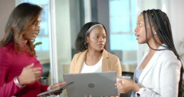 Çeşitli iş arkadaşları güncellemeleri tablet üzerinde paylaşıyor, dizüstü bilgisayarla kafa sallıyor ve toplantıda kahve fincanı tutuyor. İşbirliği, takım çalışması, iletişim, profesyonel, modern, iş dünyası, tartışma