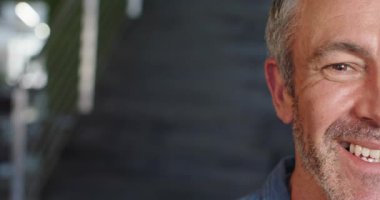 Kamera yaşlı adamı bulanık merdivenlerin yanında gülümserken görüyor portre için tırabzanlar, fotokopi alanı. Vesikalık, profesyonellik, sıcak ifade, samimi, çağdaş, portre, olgun