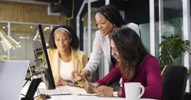 Çeşitli kadın çalışanlar monitörde hata fark ediyor, işaret ediyor, not yazıyor, ofis masasında başını sallıyor. İşbirliği, takım çalışması, profesyonel, modern, odaklanma, tartışma, iletişim