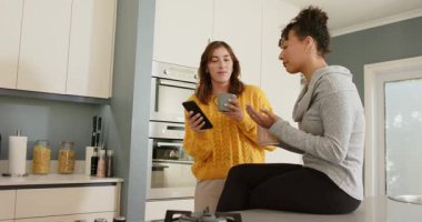 Çeşitli bayan arkadaşlar akıllı telefon ekranını paylaşarak ve bardakları yudumlayarak mesajı tartışıyorlar. Dostça sohbet, samimiyet, gündelik, yaşam tarzı, iletişim, modern