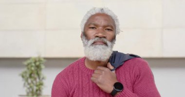 Kıdemli Afrikalı Amerikalı adam lobiye giriyor koyu renk ceketini giyiyor ve bakışlarını düzeltiyor, kendine güvenini gösteriyor. Profesyonel, kendine güvenen, şık, modern, sofistike, olgun, şehirli