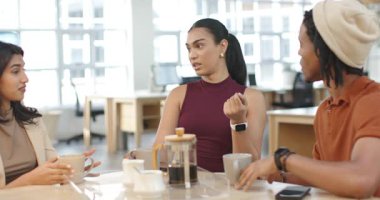 Ofisteki çeşitli iş arkadaşları fikirlerini paylaşıyorlar bordo rengi üstteki kadın kahve içerken el kaldırıyor. İşbirliği, iletişim, takım çalışması, modern, profesyonel, beyin fırtınası, tartışma