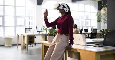 Ofiste VR kulaklık takan Hintli bir kadın tasarım incelemesi için sanal kontrollere dokunuyor. Teknoloji, yenilik, birlikte çalışma, dijital, işbirliği, fütüristik, çalışma alanı