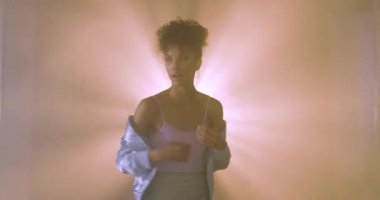 Grunge tarzı genç bir kadın puslu stüdyo ışıklarıyla rahatça poz veriyor. Moda, alternatif, kentsel, kenar, portre, moda